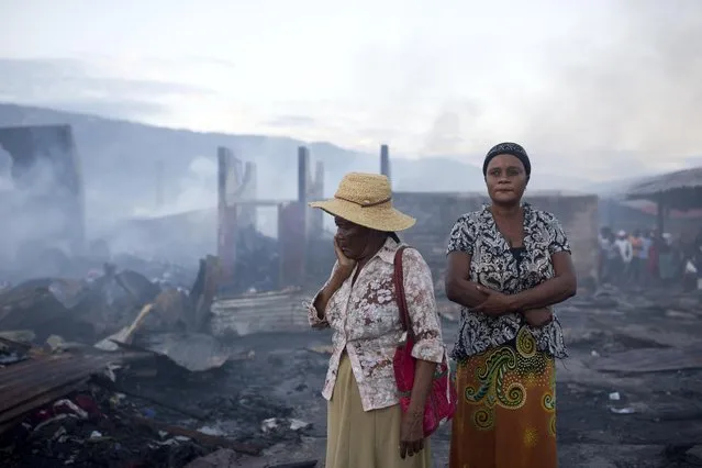 Women stand in the smoldering remains after a fire at a market in Port-au-Prince, Haiti, Monday March 20, 2017. A fire has engulfed much of a popular marketplace in Haiti's capital where hundreds of impoverished vendors sell their wares. The flames have destroyed numerous wooden stalls and a warehouse storing inventory including fabrics and used clothes. There are no reports of deaths or injuries. Despondent vendors at Port-au-Prince's sprawling Croix de Boussales market are picking through the ashes Monday looking for anything to salvage. The blaze started sweeping through the market late Sunday. The cause isn't immediately known. (Photo by Dieu Nalio Chery/AP Photo)