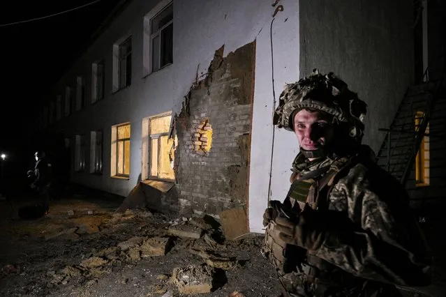 An Ukrainian soldier stands guard near debris after the reported shelling of a kindergarten in the settlement of Stanytsia Luhanska, Ukraine, on February 17, 2022. U.S. Defence Secretary Lloyd Austin warned on February 17, 2022, of a provocation by Moscow to justify military intervention in Ukraine after “disturbing” reports of mutual accusations of bombing between the Ukrainian military and pro-Russian separatists. (Photo by Aris Messinis/AFP Photo)