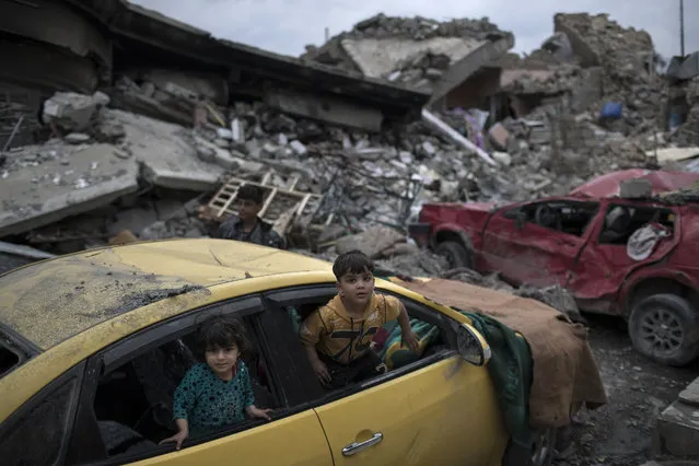 Children play inside a damaged car, amid heavy destruction in a neighborhood recently retaken by Iraqi security forces from Islamic State militants on the western side of Mosul, Iraq, Saturday, April 1, 2017. (Photo by Felipe Dana/AP Photo)