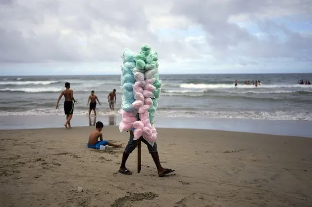 A person sells cotton candy at the beach during carnival celebration in La Guaira, Venezuela, Monday, February 28, 2022. (Photo by Ariana Cubillos/AP Photo)