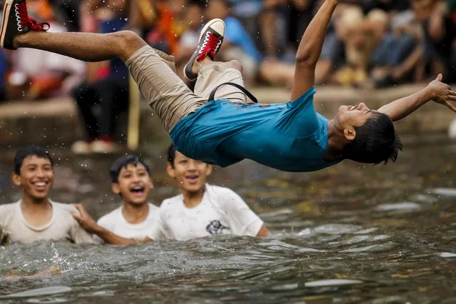 A Nepalese youth jumps on the Gahana Pokhari -A Jwel Pond before participating in a Gahana Khojne festival in Kathmandu, Nepal, 16 April 2014. Hundreds of local youths carry chariot of Goddess “Tudaldev” to search goddess lost Jwellery during a traditional 'Gahana Khojne Jatra' which means “searching for jewels” at the pond. (Photo by Narendra Shrestha/EPA)