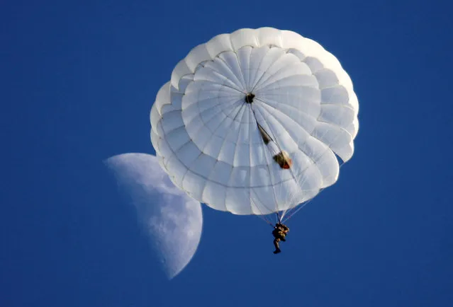 A student of the General Yermolov Cadet School is pictured after jumping with parachute from an airplane, as the moon is seen in the sky, in the village of Novomaryevskaya outside the southern city of Stavropol, Russia, May 13, 2016. (Photo by Eduard Korniyenko/Reuters)