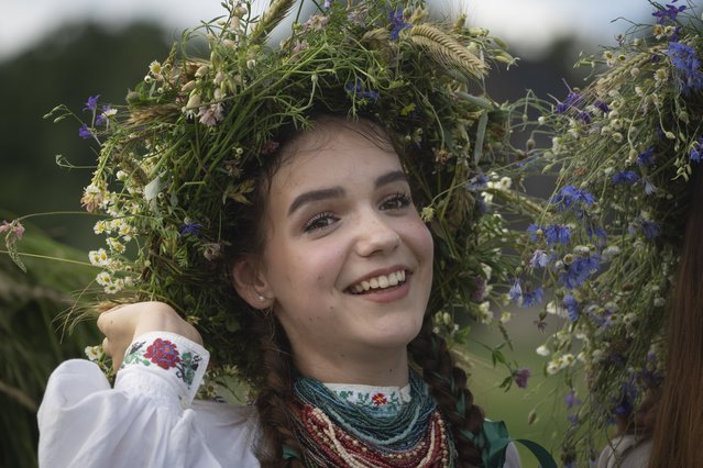 A girl with a ritual garland headdress smiles during a traditional Midsummer Night celebration near capital Kyiv, Ukraine, Sunday, June 23, 2024. The age-old pagan festival is still celebrated in Ukraine amid the third year of Russia-Ukraine war. (Photo by Efrem Lukatsky/AP Photo)