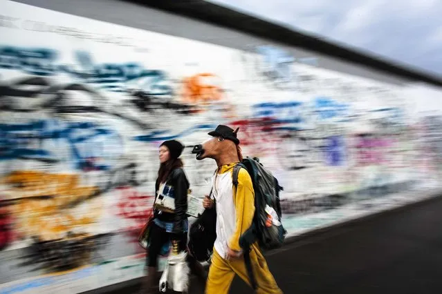 A street musician who calls  himself, “The Neigh Kid Horse”, walks in front of the remains of the Berlin Wall Germany, on May 12, 2014. (Photo by Markus Schreiber/Associated Press)