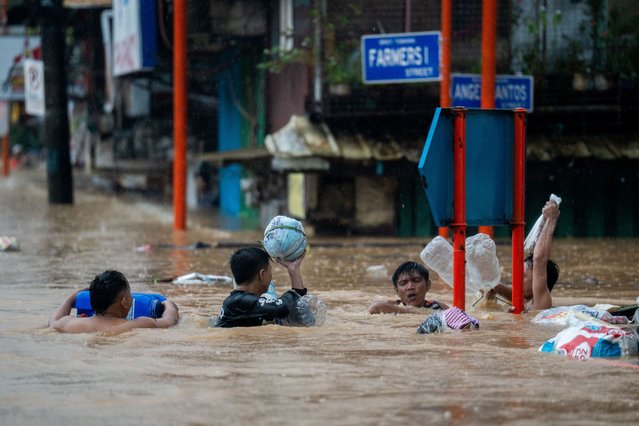 Residents wade through a flooded road following heavy rains brought by Typhoon Gaemi, in Marikina City, Metro Manila, Philippines, on July 24, 2024. (Photo by Lisa Marie David/Reuters)