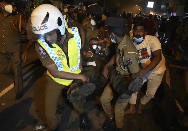 Sri Lankan police officers carry an injured officer during a protest out side Sri Lankan president's private residence on the outskirts of Colombo, Sri Lanka, Friday, April 1, 2022. (Photo by Eranga Jayawardena/AP Photo)