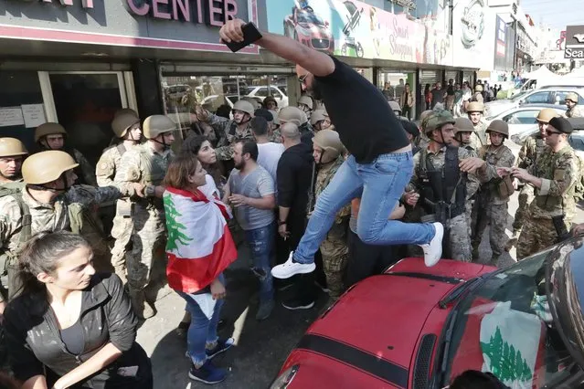 Anti-government protesters scuffle with Lebanese army soldiers in the town of Zouk Mosbeh, north of Beirut, Lebanon, Tuesday, November 5, 2019. Lebanese troops deployed in different parts of the country Tuesday reopening roads and main thoroughfares closed by anti-government protesters facing resistance in some areas that led to scuffles. (Photo by Hassan Ammar/AP Photo)