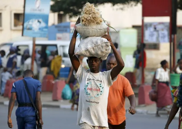 A man carries bags of vegetables at marketplace in Burundi's capital Bujumbura, as the country awaits the results of Tuesday's presidential elections, July 23, 2015. Opposition politicians have accused President Pierre Nkurunziza of violating the constitution by running for a third term and boycotted the election in the world's third poorest country. (Photo by Mike Hutchings/Reuters)