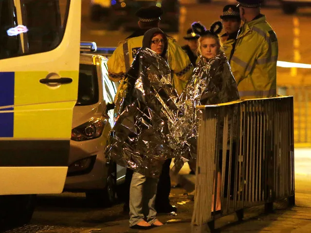 Two women wrapped in thermal blankets stand near the Manchester Arena, where U.S. singer Ariana Grande had been performing, in Manchester, northern England, Britain, May 23, 2017. (Photo by Andrew Yates/Reuters)