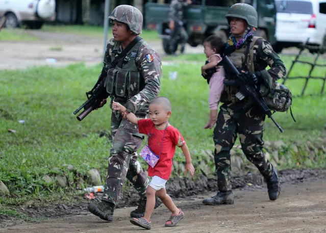 Filipino soldiers hold on to fleeing children following reports of fresh clashes between government troops and rebels in Marawi City, Mindanao Island, southern Philippines, 25 May 2017. According to media reports, President Rodrigo Duterte declared martial law on the southern island of Mindanao in response to a new armed offensive by the Maute group, one of the jihadist bands operating in the region. On May 23, militants from the Maute group – an organization linked to the so-called Islamic State (or IS or ISIS) – had captured Marawi, a city with a population of 200,000 people, and laid siege on a hospital for hours, and set a church, a college and the city's prison to fire, while holding over 10 people hostage. The Maute group is an Islamic armed organization based in Lanao del Sur that first emerged in 2012 under the name of Khilafah Islamiyah Movement (KIM), but adopted the name EI-Ranao two years later to indicate its affiliation with the so-called Islamic State. (Photo by Linus G. Escandor Ii/EPA)