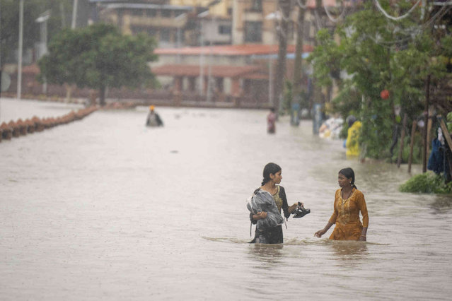 Women walk with their belongings on the flooded banks of the Bagmati river following heavy monsoon rains in Kathmandu, Nepal, Saturday, July 6, 2024. (Photo by Niranjan Shrestha/AP Photo)