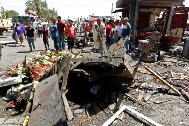 Iraqis gather at the site of a car bomb explosion near Baghdad's  Al-Shuhada Bridge on May 30, 2017 which killed at least five people and wounded 17, security and medical officials said. There was no immediate claim of responsibility for the attack but the Islamic State group carries out frequent bombings targeting civilians in the Iraqi capital. The blast followed an overnight suicide bombing at a popular Baghdad ice cream shop that killed at least 21 people. (Photo by Sabah Arar/AFP Photo)