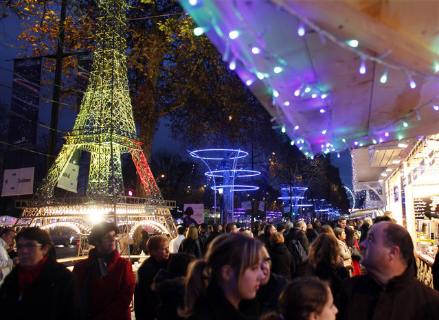 France: Shoppers visit the Christmas market along the Champs Elysees in Paris, December 3, 2011. At left is a model of the Eiffel Tower. (Photo by Mal Langsdon/Reuters)