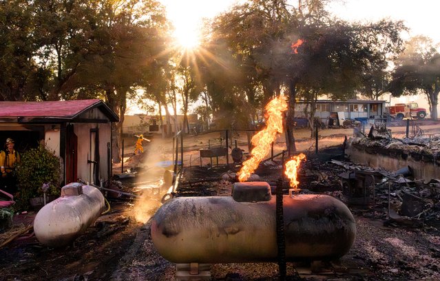 Flames emerge from a propane tank near a smoldering property as the Boyles Fire burns in Clearlake, California, on September 8, 2024. The fire has thus far burned at least 30 homes and is being investigated for arson. (Photo by Josh Edelson/AFP Photo)