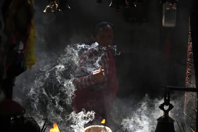 A woman lights incense while she offers prayers during Holi festival in Bhaktapur, Nepal, Thursday, March 17, 2022. The festival marks the advent of spring. (Photo by Niranjan Shrestha/AP Photo)