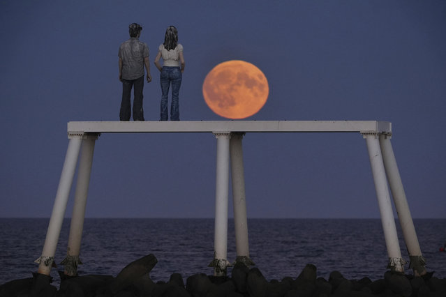 The full Harvest moon rises over “The Couple” sculpture at Newbiggin-by-the-Sea in Northumberland, Tuesday September 17, 2024. ((Photo by Owen Humphreys/PA Wire via AP Photo)