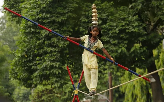 An Indian street performer Shanti, 8, walks a tightrope in Allahabad, India, Wednesday, July 16, 2014. Shanti and her two siblings perform on streets and earn about Rupees 12000-16000 (US$203-271) in a month. (Photo by Rajesh Kumar Singh/AP Photo)