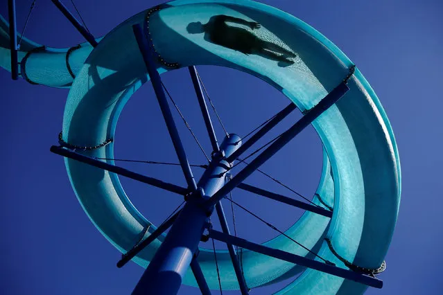 A visitor is silhouetted while sliding down a huge water pipe on a hot and sunny day at a public swimming pool in Vienna, Austria July 5, 2017. (Photo by Leonhard Foeger/Reuters)