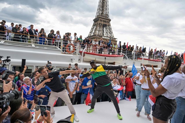 Jamaican sprinter Usain Bolt (C-R) and French designer of the Olympic torch Mathieu Lehanneur (C-L) pose during the torch's presentation on the the river Seine, as the landmark Eiffel Tower is seen in background, in Paris, on July 25, 2023, ahead of the Paris 2024 Olympic and Paralympic Games. (Photo by Alain Jocard/AFP Photo)