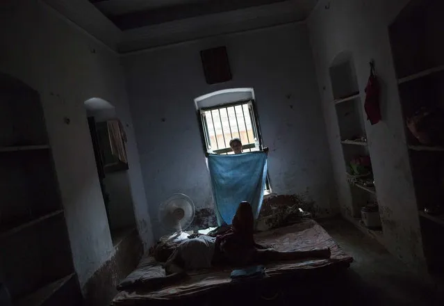 Kishore Pandey, 82, lies on a bed as his daughter Neelam Tiwari folds a cloth at Mukti Bhavan (Salvation House) in Varanasi, in the northern Indian state of Uttar Pradesh, June 17, 2014. (Photo by Danish Siddiqui/Reuters)