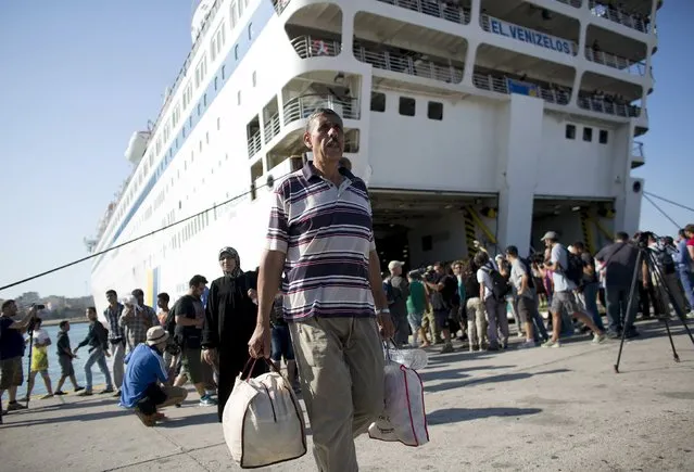 A Syrian refugee man carries his luggage as he walks out of “Eleftherios Venizelos” passenger ship after its arrival at the port of Piraeus near Athens, Greece, August 20, 2015. (Photo by Stoyan Nenov/Reuters)