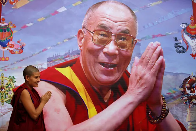 A Tibetan nun poses for a friend taking pictures near the portrait of Dalai Lama during his birthday celebration in Kathmandu, Nepal, July 6, 2016. (Photo by Navesh Chitrakar/Reuters)