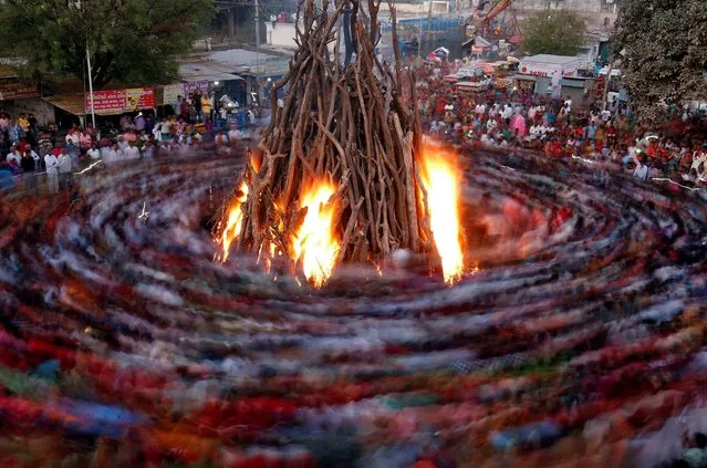 Hindu devotees walk around a bonfire during a ritual known as “Holika Dahan” which is part of Holi festival celebrations, in Ahmedabad, India, March 9, 2020. (Photo by Amit Dave/Reuters)