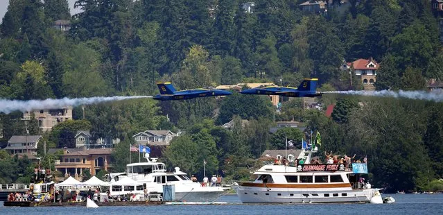 Two U.S. Navy Blue Angels make a narrow pass past each other as they fly over boats on Lake Washington during the Seafair Air Show, Sunday, August 3, 2014, in Seattle. The races are part of Seattle's annual Seafair weekend. (Photo by Ted S. Warren/AP Photo)