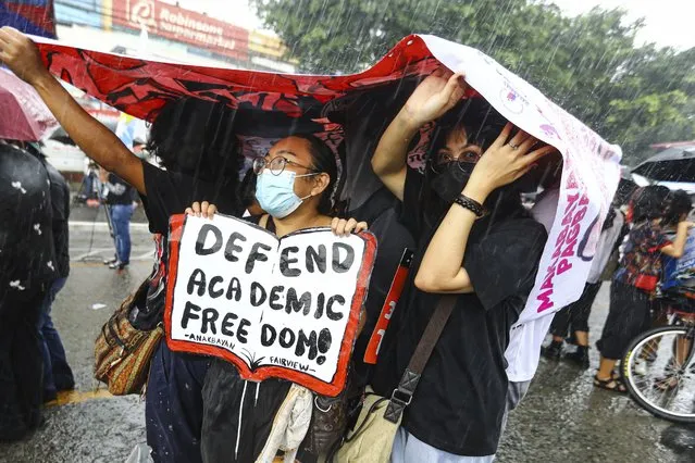 Protesters use banners as rain cover during a suddenn downpour at a rally against the State of the Nation address in Quezon City, Philippines Monday, July 25, 2022. Philippine President Ferdinand Marcos Jr. will deliver his first State of the Nation address Monday with momentum from his landslide election victory, but he's hamstrung by history as an ousted dictator’s son and daunting economic headwinds. (Photo by Gerard Carreon/AP Photo)