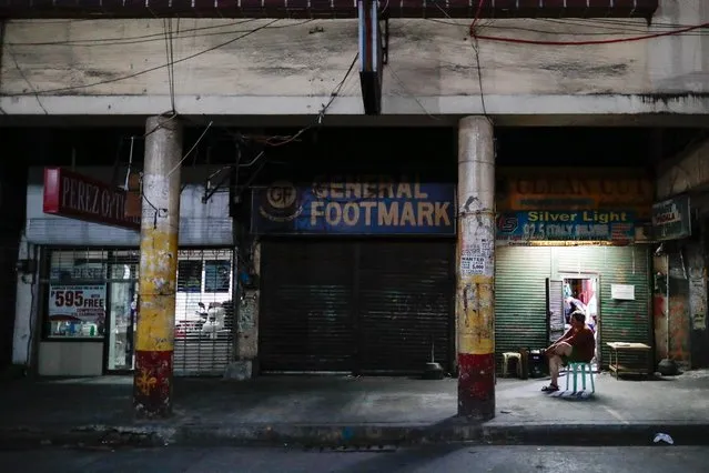 A man sits outside closed shops following the lockdown in the Philippine capital to prevent the spread of the coronavirus disease (COVID-19), in Manila, Philippines, March 24, 2020. (Photo by Eloisa Lopez/Reuters)