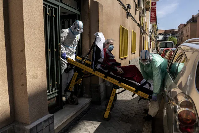 Enrique, a 92 year old man is taken out of his home by medics to a waiting ambulance after he showed signs of possible coronavirus symptoms with serious breathing problems in Madrid, Spain, Sunday, April 12, 2020. Spain will allow workers in industry and construction to return to work after a two-week shutdown of economic activities other than health care and the food industry. That lockdown has threatened to send the country into recession. (Photo by Olmo Calvo/AP Photo)