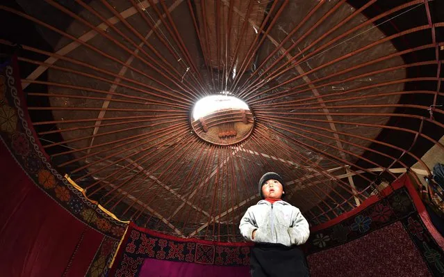 A boy stands in the yurt, the traditional portable dwelling on nomads on the Suusamyr Plateau, 2,500 meters above sea level, close to the ancient network of trade routes of the Silk Road between East and West, some 200 kilometres from Bishkek, the capital of Kyrgyzstan, on August 10, 2022. (Photo by Vyacheslav Oseledko/AFP Photo)