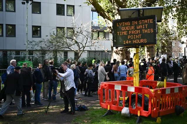 A digital sign board displays the queueing time as members of the public stand in the queue at Southwark Park, as they wait in line to pay their respects to the late Queen Elizabeth II, in London on September 16, 2022, where her coffin is lying in state on the catafalque in Westminster Hall at the Palace of Westminster Queen Elizabeth II will lie in state until 0530 GMT on September 19, a few hours before her funeral, with huge queues expected to file past her coffin to pay their respects. (Photo by Marco Bertorello/AFP Photo)