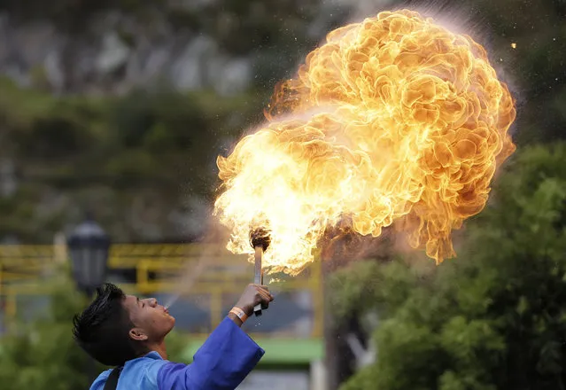 A young fire breather marches in a parade as part of the XXII National Andina Dance Competition's opening ceremony in Nemocon, Colombia, Saturday, September 6, 2014. Forty dance groups from different parts of Colombia arrived in Nemocon, just north of Bogota, to take part in the two-day national dance competition. (Photo by Fernando Vergara/AP Photo)