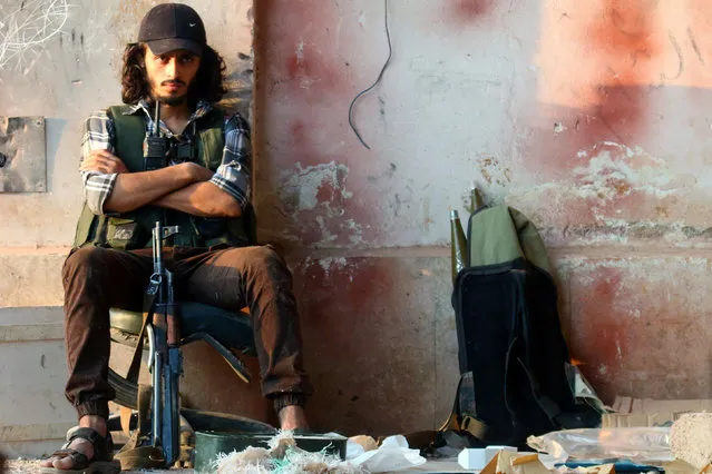 A rebel fighter sits with his weapon in the artillery academy of Aleppo, Syria, August 6, 2016. (Photo by Ammar Abdullah/Reuters)