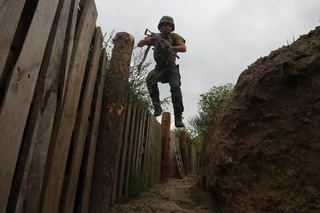 A member of the Ukrainian National Guard jumps into a trench at a position near a front line, as Russia's attack on Ukraine continues, in Kharkiv region, Ukraine on August 3, 2022. (Photo by Vyacheslav Madiyevskyy/Reuters)