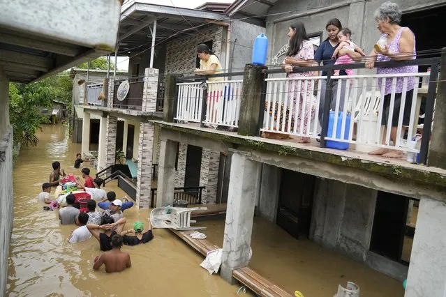 Residents stay on the deck of their house as others negotiate a flooded road due to Typhoon Noru in San Miguel town, Bulacan province, Philippines, Monday, September 26, 2022. (Photo by Aaron Favila/AP Photo)