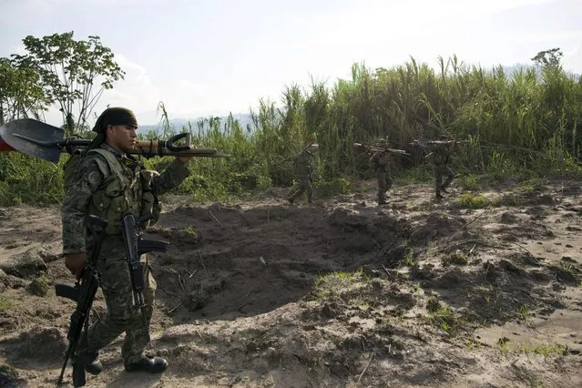 In this September 19, 2014 photo, soldiers walk around a crater created by explosives planted by Peruvian counternarcotics forces on part of a clandestine grassy airstrip, located in the Apurimac, Ene and Mantaro River Valleys, or VRAEM, the world's No. 1 coca-growing region, in Ayacucho, Peru. According to authorities traffickers pay local villagers up to $100 each to fill the holes blasted into the landing strips that dot the floodplain. (Photo by Rodrigo Abd/AP Photo)
