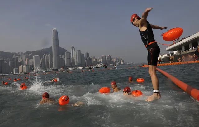 A competitor jumps in the water to swim during the annual 1-kilometer (0.6-mile) harbor race at the Victoria Harbour in Hong Kong, Sunday, October 29, 2017. Thousands of swimmers have taken part in a new version of Hong Kong's iconic cross harbor race. The swimming race was suspended for six years because of concerns about water pollution. (Photo by Vincent Yu/AP Photo)