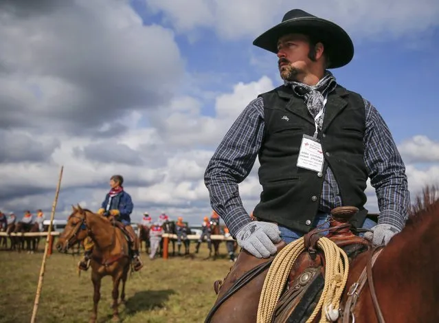 Farm manager Shane Stotlar of the U.S. watches the competition during the Russian Rodeo in the village of Kotliakovo, Bryansk region, southeast of Moscow, Russia, September 12, 2015. (Photo by Maxim Shemetov/Reuters)
