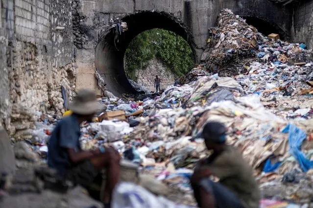A man looks through piles of trash on a stream in Port-au-Prince, Haiti on October 13, 2022. (Photo by Ricardo Arduengo/Reuters)