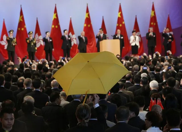 Paul Zimmerman, a district councillor, raises a yellow umbrella as Hong Kong Chief Executive Leung Chun-ying (5th R) and other officials make a toast to guests at a reception following a flag raising ceremony in Hong Kong October 1, 2014, celebrating the 65th anniversary of China National Day. As tensions subsided, weary protesters dozed or sheltered from the sun beneath umbrellas. (Photo by Bobby Yip/Reuters)