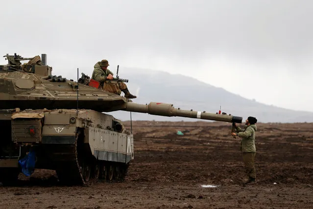 An Israeli soldier sits atop a tank and his comrade stands nearby in the Israeli-occupied Golan Heights, close to Israel's frontier with Syria November 22, 2017. (Photo by Ammar Awad/Reuters)