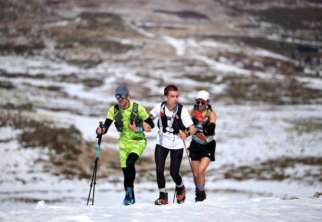 Victor Asenov, a visually impaired ultramarathon runner, is guided by pacers Pavlin Beev and Veradina Nacheva as he attempts to cover the same elevation as Mount Everest, an activity known as “Everesting”, by running up and down the Black Peak summit of the Vitosha mountain, to raise awareness of a guide dog school, near Sofia, Bulgaria, on March 21, 2025. (Photo by Spasiyana Sergieva/Reuters)