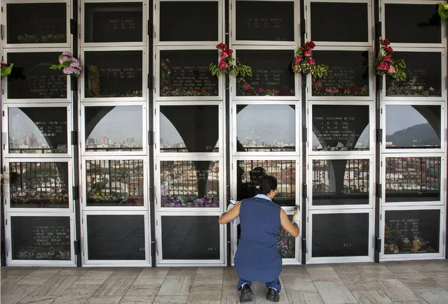 In this Oct. 13, 2014 photo, an employee at the Necropole Ecumenica Memorial cleans the surface of crypts in Santos, Brazil. When completed, the five building memorial known as a vertical cemetery will hold 180,000 bodies. (AP Photo/Andre Penner)