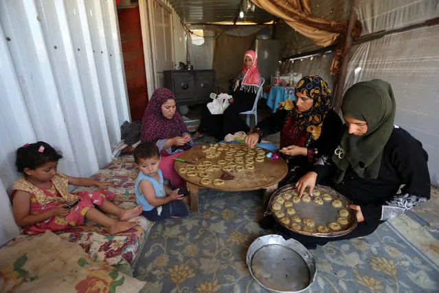 A Palestinian family, whose house was destroyed during 2014 war, make traditional cakes inside their makeshift shelter, ahead of Eid-al-Fitr celebrations in Khan Younis in the southern Gaza Strip July 3, 2016. (Photo by Ibraheem Abu Mustafa/Reuters)