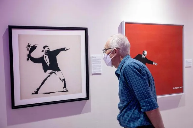 A visitor views “Flower Thrower, 2002” by British street artist Banksy on the opening day of the Art of Banksy: Without Limits exhibition at the Museum of Contemporary Art (MOCA) in Bangkok on October 26, 2022. (Photo by Jack Taylor/AFP Photo)