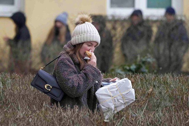 A young woman eats one of the marmalade-filled doughnuts, or paczki, that she had queued for over 4 hours to buy at a renowned bakery and follow Poland's tradition of eating them on Fat Thursday that ends carnival, in Warsaw, Poland, Thursday February 8, 2024. (Photo by Czarek Sokolowski/AP Photo)