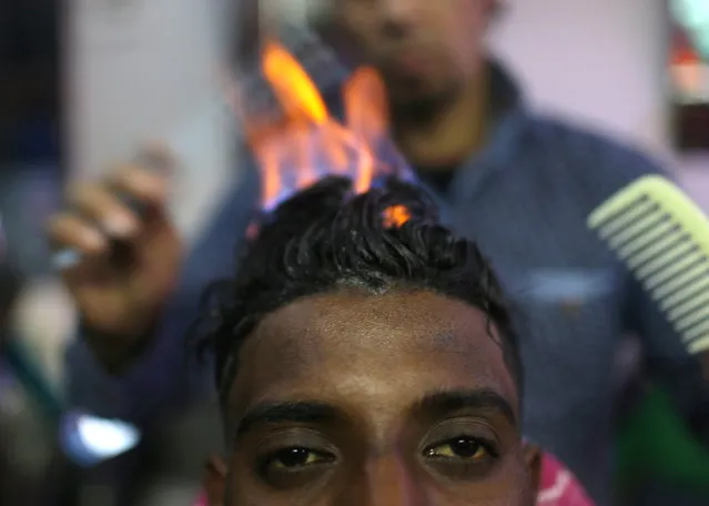 Palestinian barber Ramadan Odwan styles and straightens the hair of a customer with fire at his salon in Rafah, in the southern Gaza Strip February 2, 2017. (Photo by Ibraheem Abu Mustafa/Reuters)
