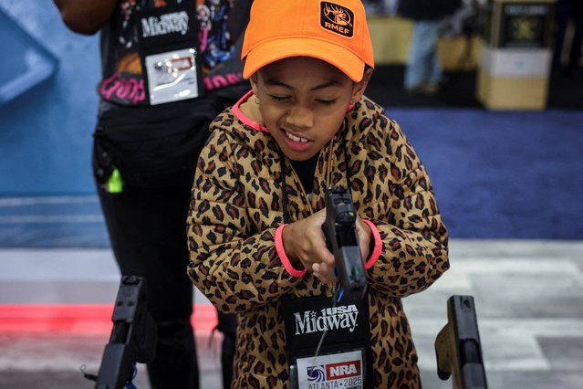 A girl holds a gun at a booth during the NRA annual meeting in Atlanta, Georgia, U.S. April 26, 2025. (Photo by Jeenah Moon/Reuters)